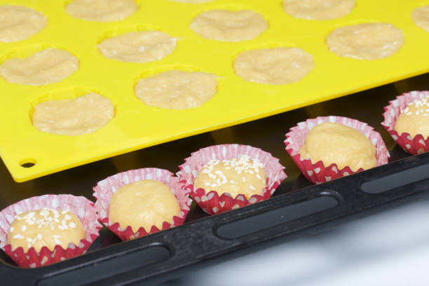 istock On the baking sheet is a silicone mold with a dough. Also small paper forms filled with dough. 968469678
