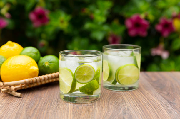 Brazilian drink Caipirinha with ingredients on wooden table and plants on the background. Copy space.