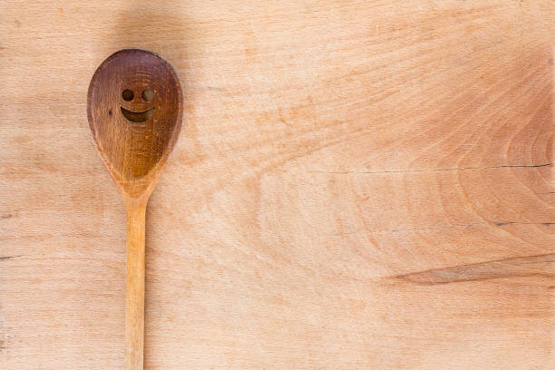 Wooden smiley face spoon on a wooden background. Studio shot. Set of kitchen utensil.