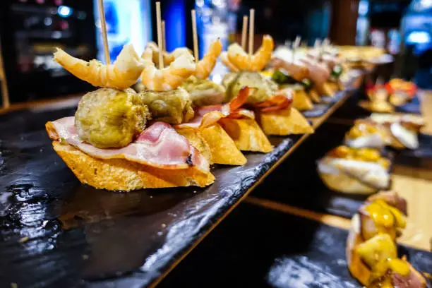 Spanish Pintxos (Pincho) from the Basque region of Bilbao and San Sebastian.

A typical snack of the Basque Country and Navarre, "pinchos" (Pintxos) consist of small slices of bread upon which an ingredient or mixture of ingredients is placed and fastened with a toothpick, which gives the food its name "pincho", meaning "spike." Pinchos are very common in the taverns of the Basque Country.