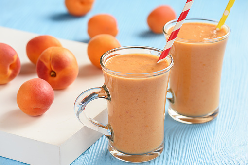 Apricot smoothie, healthy beverage, on wooden background.