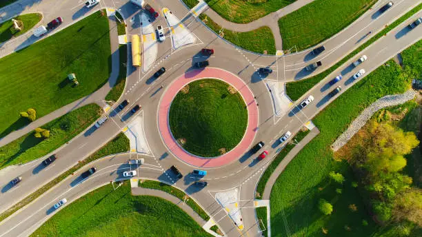Early morning rush hour at busy city roundabout, aerial view.