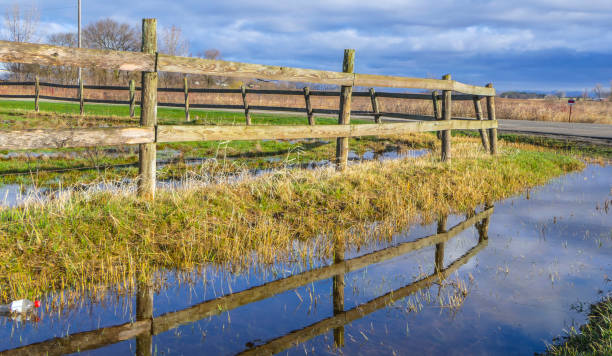 istock Rustic countryside wooden fence reflected in Springtime puddle. 968523500