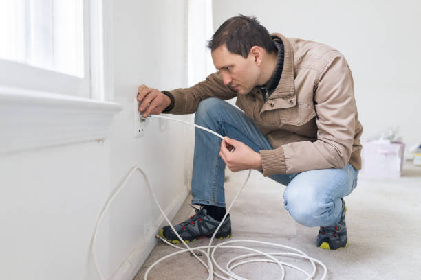 istock Young man installing cable television internet wire in room wall carpet floor flooring, white walls, during remodeling inspection renovation 968523870