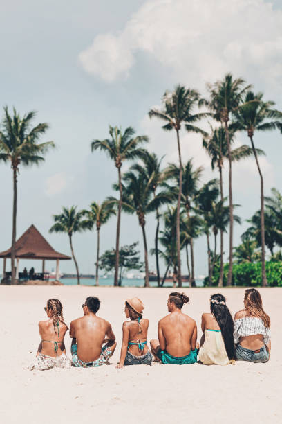 istock Group of young people sitting on the beach 968532826