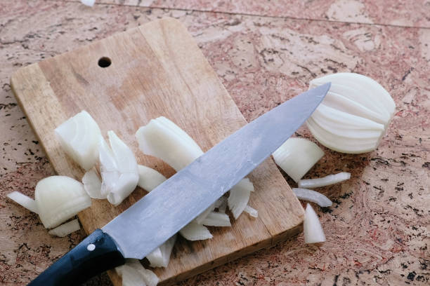 istock Knife and onion pieces on a wooden board. 968539176
