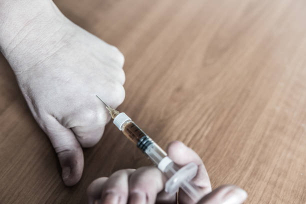 Person sets a syringe needle with heroin stock photo