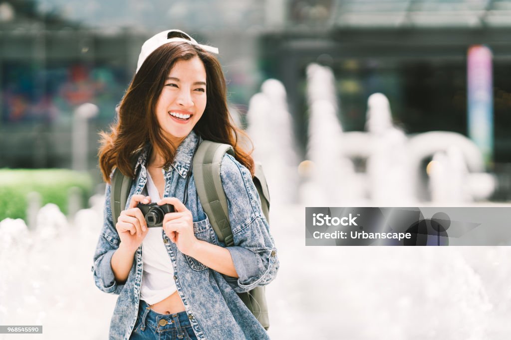 Mochila asiática hermosa joven viajero mujer usando cámara digital compacta y sonrisa, mirando el espacio de la copia. Estilo de vida de viaje viaje, mundo travel explorer o concepto de turismo de verano de Asia - Foto de stock de Asia libre de derechos