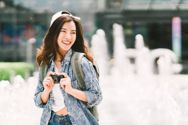 mochila asiática hermosa joven viajero mujer usando cámara digital compacta y sonrisa, mirando el espacio de la copia. estilo de vida de viaje viaje, mundo travel explorer o concepto de turismo de verano de asia - cámara digital fotos fotografías e imágenes de stock