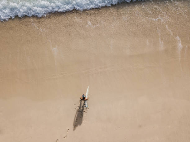 istock Surfer walking over sand beach holding a surfboard 968551810