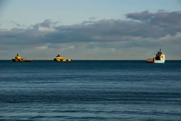 Three Oilrig supply vessels anchored off Aberdeen North beach outside Aberdeen harbour in the North Sea.