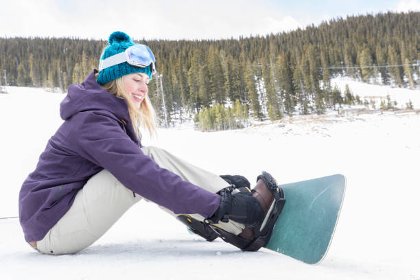 istock Young woman adjusts snowboard 968605756