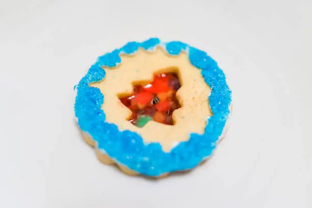 One decorated icing glazed with candy sugar colorful artificial blue sprinkles macro closeup Christmas holiday baked homemade cookie, tree isolated on plate