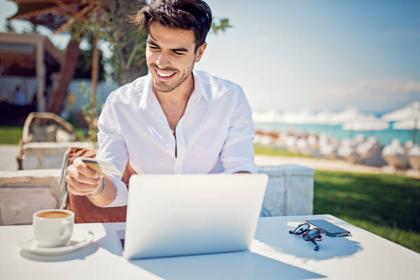 istock Man is shopping online/making reservation on the beach 968606748