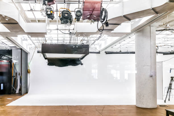 Empty large commercial photography video studio with equipment, lights and white backdrop
