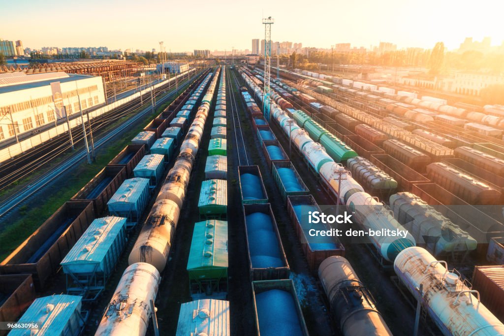 Vue aérienne de trains de marchandises colorées. Wagons de fret sur la gare. Wagons à marchandises sur le chemin de fer. Industrie lourde. Paysage industriel avec train, chemin de fer platfform au coucher du soleil. Vue de dessus. Dépôt. - Photo de Fret libre de droits