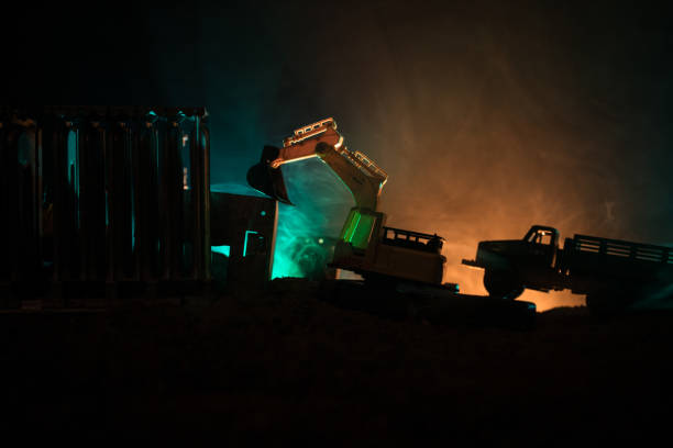 istock Construction site on a city street. A yellow digger excavator parked during the night on a construction site. Industrial concept table decoration on dark foggy toned background 968631214