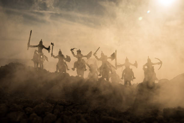Medieval battle scene with cavalry and infantry. Silhouettes of figures as separate objects, fight between warriors on sunset foggy background. Medieval battle scene with cavalry and infantry. Silhouettes of figures as separate objects, fight between warriors on sunset foggy background. Selective focus battlefield photos stock pictures, royalty-free photos & images