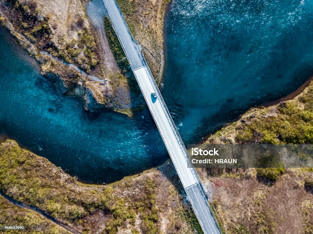 Driving on a bridge over deep blue water Birds view of a bridge over deep blue water. A car is driving over the river. Bridge - Built Structure Stock Photo