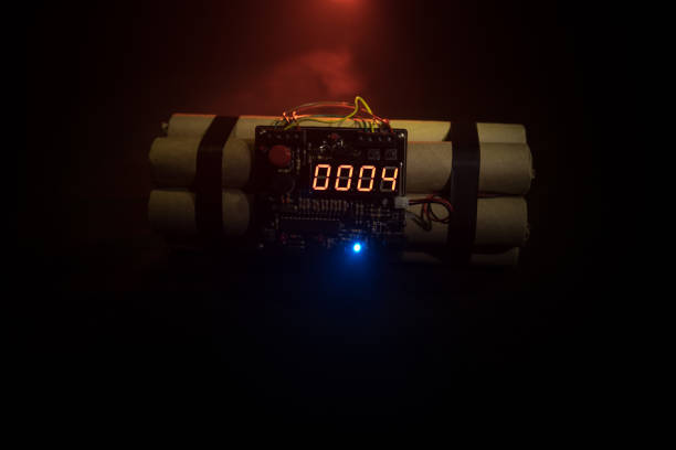 istock Image of a time bomb against dark background. Timer counting down to detonation illuminated in a shaft light shining through the darkness 968636258