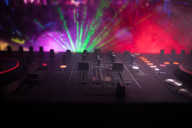 istock In selective focus of Pro dj controller.The DJ console deejay mixing desk at music party in nightclub with colored disco lights. 968636350