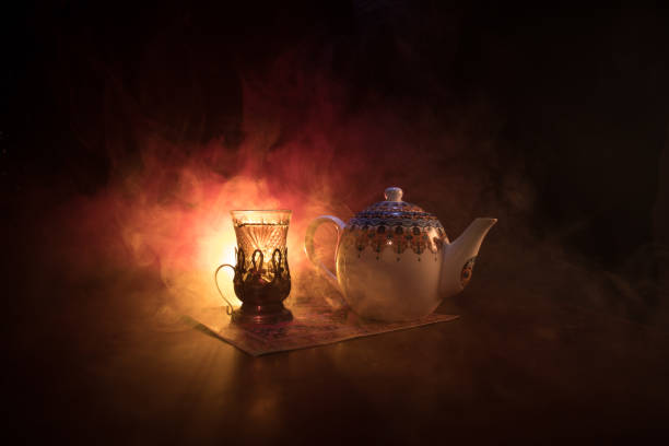 istock Eastern tea in traditional glasse and pot on black background with lights and smoke. Eastern tea concept. Armudu traditional Azerbaijan/Turkish cup 968636436