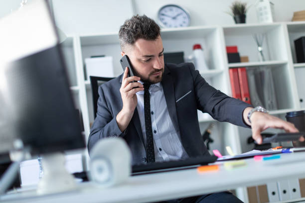 istock A man sits in the office at the desk, talks on the phone, works with documents and puts aside the calculator. 968637162