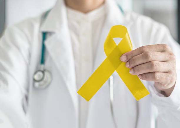 Yellow ribbon symbolic color for Sarcoma Bone cancer awareness and suicide prevention in doctorâs hand Yellow ribbon symbolic color for Sarcoma Bone cancer awareness and suicide prevention in doctorâs hand allegory painting photos stock pictures, royalty-free photos & images