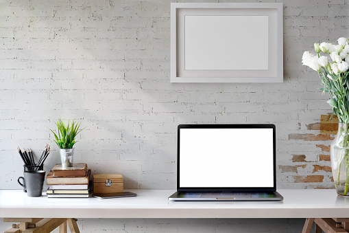 Mock Up workspace, Blank screen laptop and mockup poster on desk.