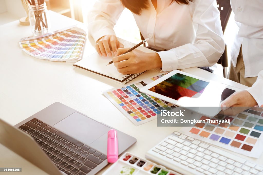 Team of creative designers working with tablet for new project in a design studio Office Stock Photo