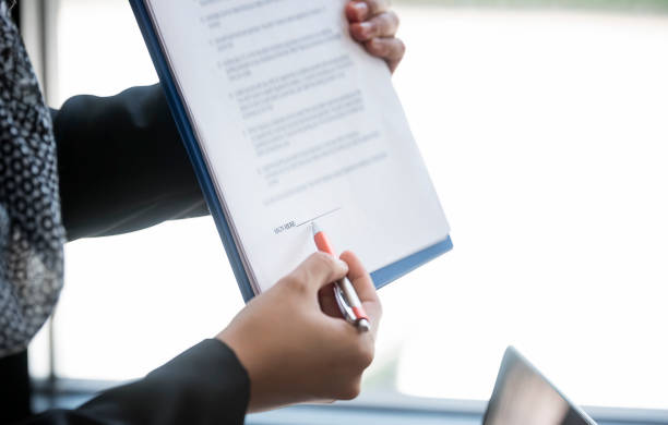 istock female hand holding pen pointing at document paper for sign contract 968671424