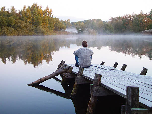 istock man alone on a pier with early morning mist 96868154