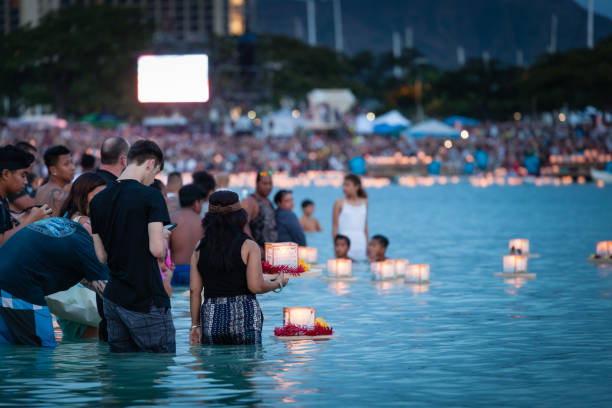 Young couple placing prayer lantern in water Honolulu, Hawaii. stock photo