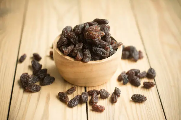 bowl of organic dried raisins. raisins on a wooden background.