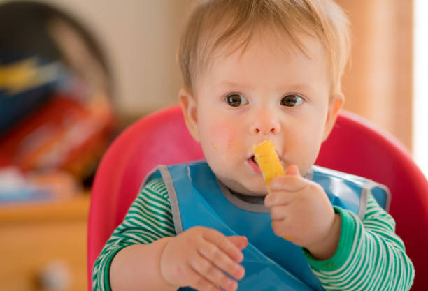 istock Baby sitting in highchair eating 968774822