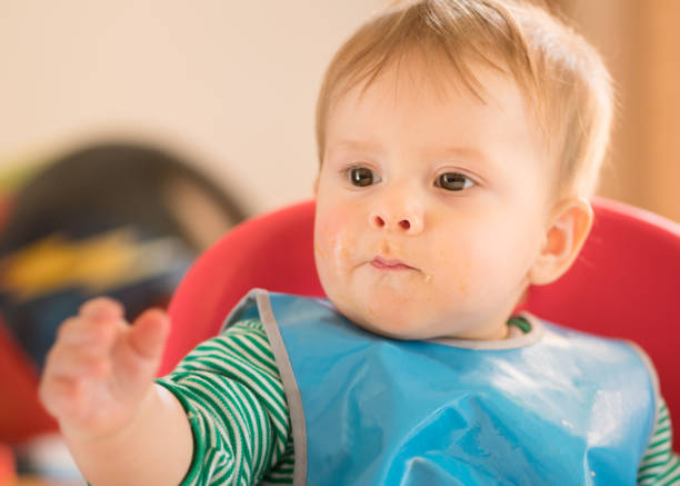 istock Baby sitting in highchair eating 968774828