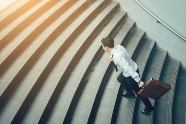 istock Businessman holding suitcase and running on stairs. 968774930