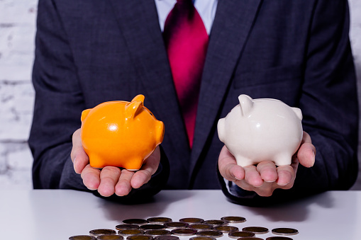 Businessman making a comparison and difference between each money piggy bank - finance issue comparison concept