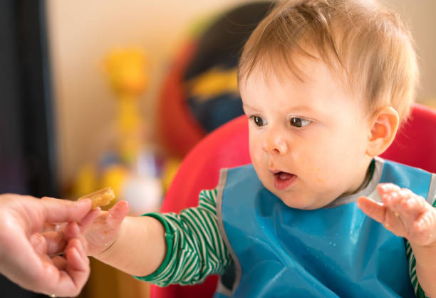 istock Baby sitting in highchair eating 968775056