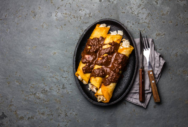 istock Mexican cuisine. Traditional Mexican chicken enchiladas with spicy chocolate salsa mole poblano. Enchiladas with sauce moole from Puebla, Mexico 968788498