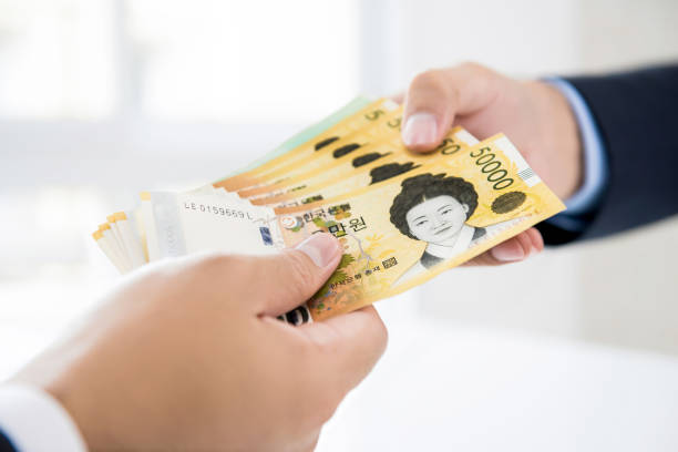 hombre de negocios dando dinero a su pareja en forma de won surcoreano - korean currency fotografías e imágenes de stock