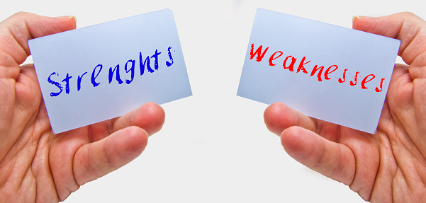 man hands holding cards with the words strenghts and weaknesses for swot analysis