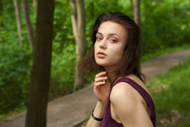 primer plano retrato de una hermosa joven de 18 años en un vestido morado en un bosque de verano - one person one young woman only 18 19 years teenage girls fotografías e imágenes de stock