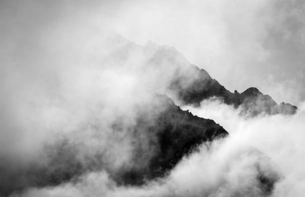Stormy mountain silhouette background A mountain peak in the alps of Switzerland in black and white surrounded by clouds silhouetted against the rising sun. swiss culture photos stock pictures, royalty-free photos & images