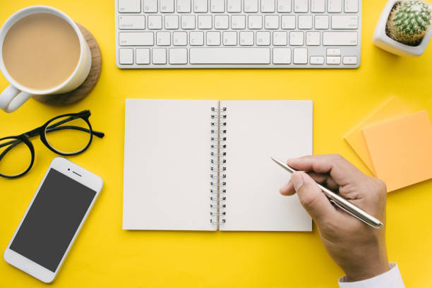 Top view of office desk table with male hand on notepad and modern accessories.flat lay design