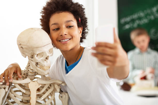 Cheerful happy teenager hugging a skeleton