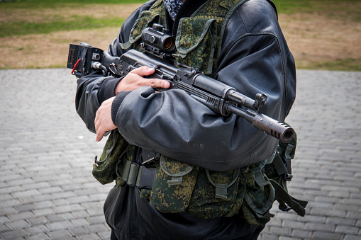 a man with a machine gun. male men's hands holding a rifle. Irregular troops. unprofessional military. Militiaman. Kalashnikov assault rifle with laser sniper scope. separatists