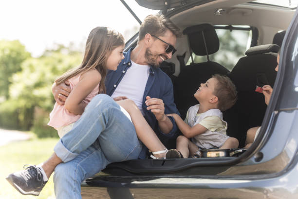 istock Two adorable kids sitting in a trunk car with father 968831064