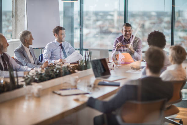 istock Happy CEO talking to his team at conference table in a board room. 968834578