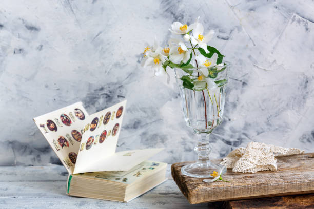 istock Sprigs of jasmine in a glass and an open old book. 968836376